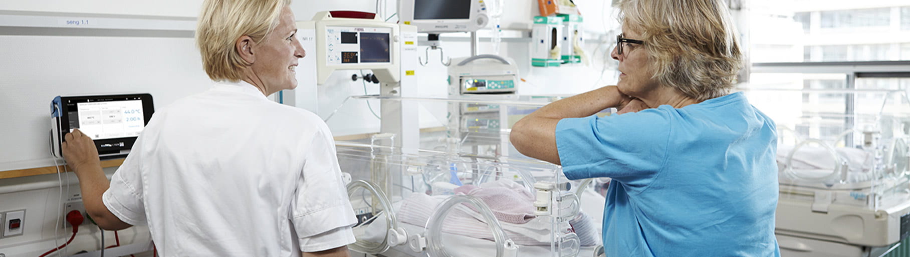 Situation hospitalière – deux soignants de l’unité de soins intensifs néonatals, utilisant un moniteur transcutané de Radiometer